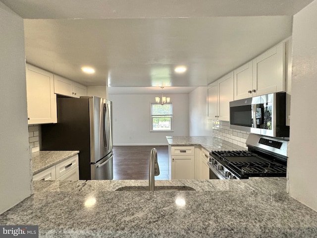 225 N New St, Dover, DE 19904 - kitchen featuring appliances with stainless steel finishes, a chandelier, wood finished floors, backsplash, and light stone counters