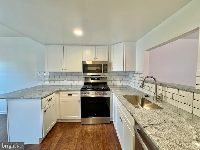 225 N New St, Dover, DE 19904 - kitchen featuring stainless steel appliances, a peninsula, white cabinetry, light stone countertops, and dark wood-style flooring