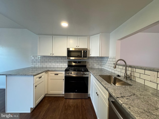 225 N New St, Dover, DE 19904 - kitchen with stainless steel appliances, a peninsula, dark wood-style flooring, and light stone countertops