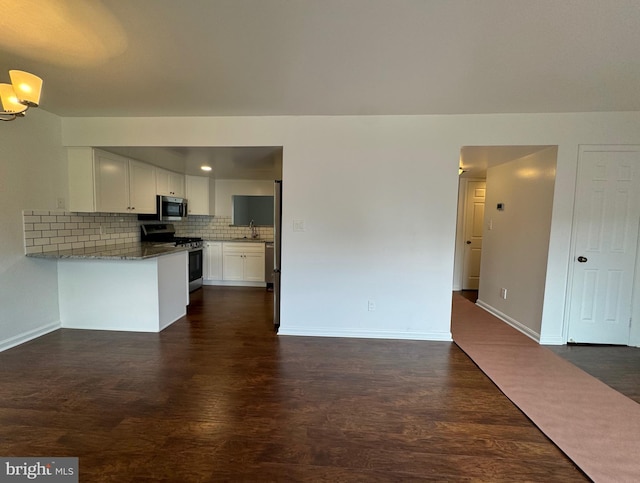 225 N New St, Dover, DE 19904 - kitchen with appliances with stainless steel finishes, dark wood-style floors, backsplash, white cabinetry, and a peninsula