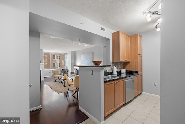 851 N Glebe Rd Unit 1508, Arlington, VA 22203 - kitchen featuring stainless steel dishwasher, track lighting, open floor plan, dark countertops, and backsplash