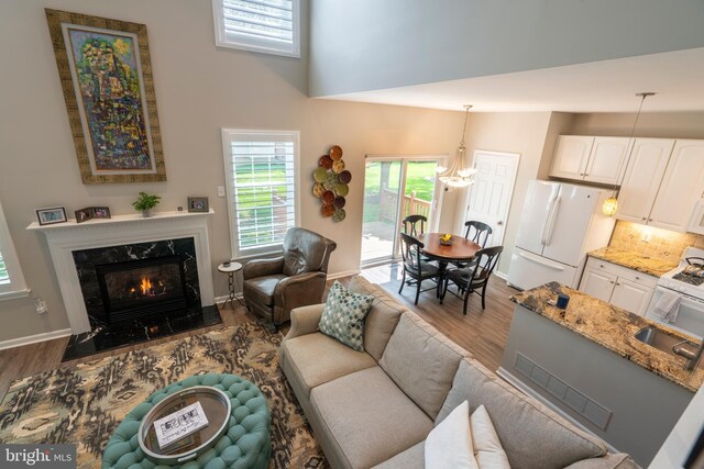 102 Warwick Way N, Wales, PA 19454 - living area featuring wood finished floors, a high end fireplace, a high ceiling, baseboards, and a chandelier
