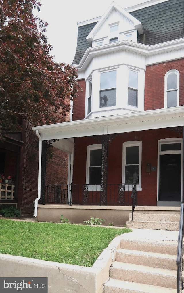 722 W King St, York, PA 17401 - view of front facade featuring covered porch, roof with shingles, brick siding, and mansard roof