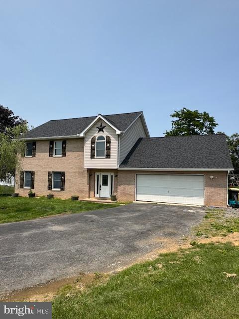 121 Defense Ct, Hedgesville, WV 25427 - traditional home featuring asphalt driveway, brick siding, an attached garage, and a front lawn