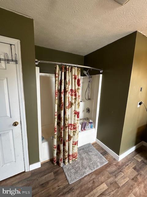 121 Defense Ct, Hedgesville, WV 25427 - bathroom featuring wood finished floors, a textured ceiling, baseboards, and shower / tub combo with curtain