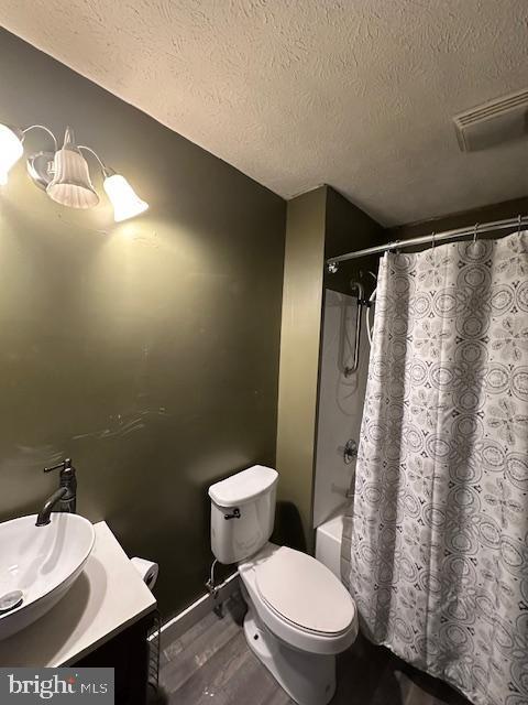 121 Defense Ct, Hedgesville, WV 25427 - bathroom featuring a textured ceiling, vanity, toilet, shower / bath combo, and wood finished floors