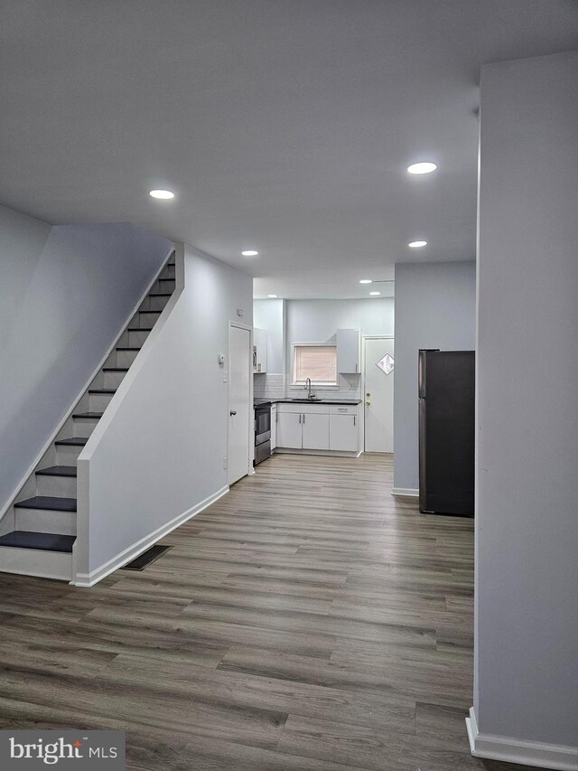 2249 Kennedy St, Philadelphia, PA 19137 - unfurnished living room featuring recessed lighting, stairs, a sink, wood finished floors, and baseboards