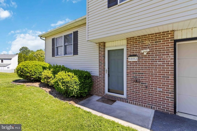 8892 Mckinley Ct, Hummelstown, PA 17036 - doorway to property with a yard, brick siding, and a garage