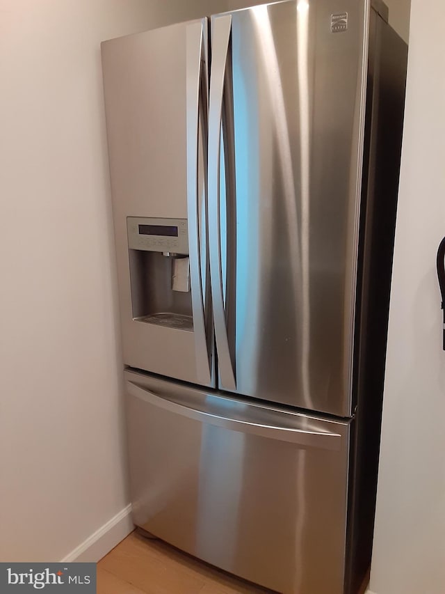 2046 Lucas Ln, Voorhees, NJ 08043 - detailed view of stainless steel refrigerator with ice dispenser, light wood-style flooring, and baseboards