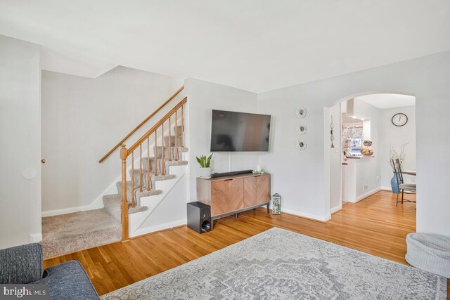 7215 Conley St, Baltimore, MD 21224 - living room with arched walkways, wood finished floors, stairs, and baseboards