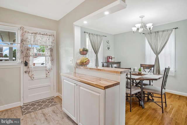 7215 Conley St, Baltimore, MD 21224 - kitchen featuring wooden counters, light wood-type flooring, a chandelier, baseboards, and white cabinets