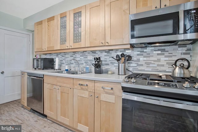 7215 Conley St, Baltimore, MD 21224 - kitchen with appliances with stainless steel finishes, light brown cabinetry, a sink, light countertops, and backsplash