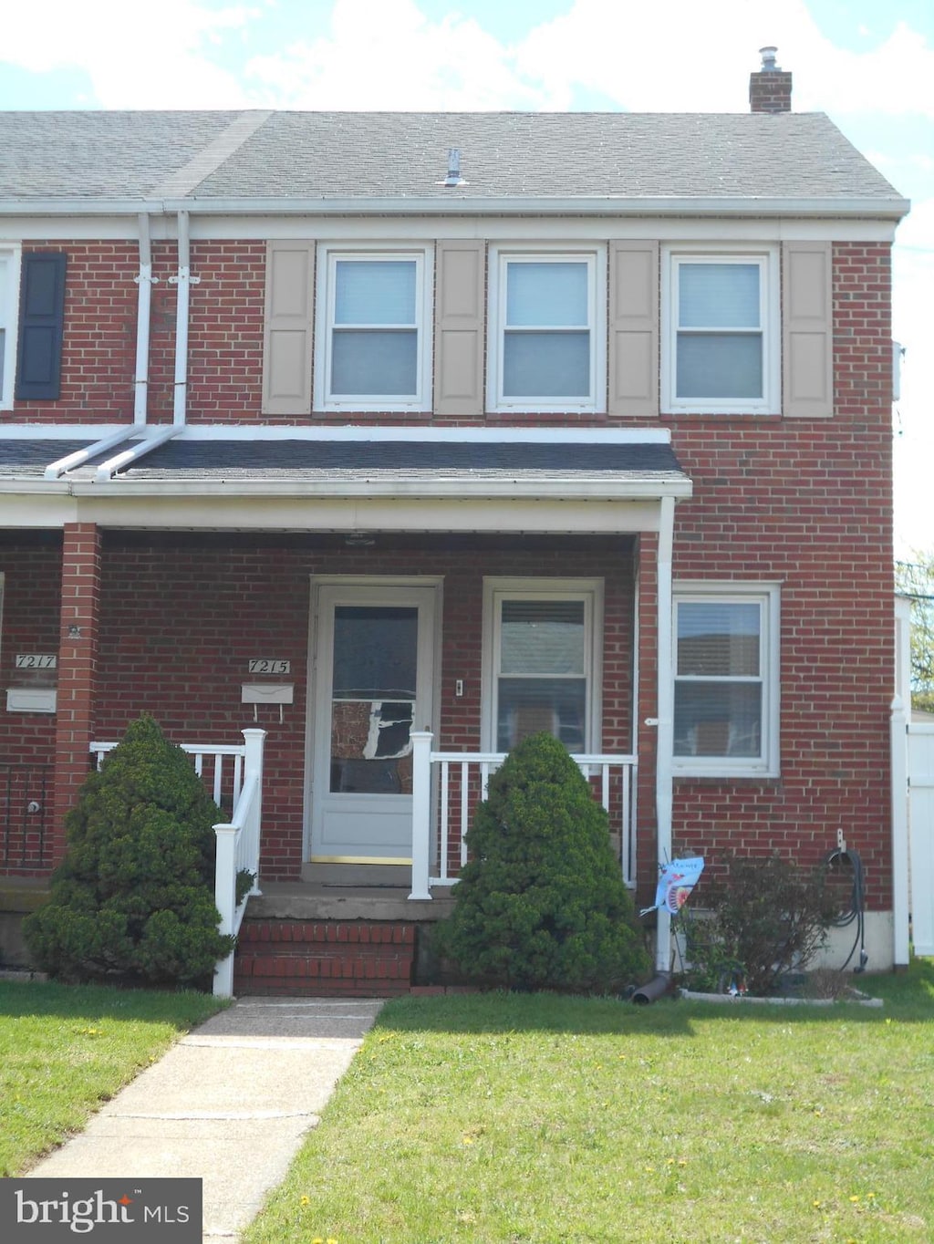 7215 Conley St, Baltimore, MD 21224 - view of property with brick siding, a chimney, a front yard, and a porch