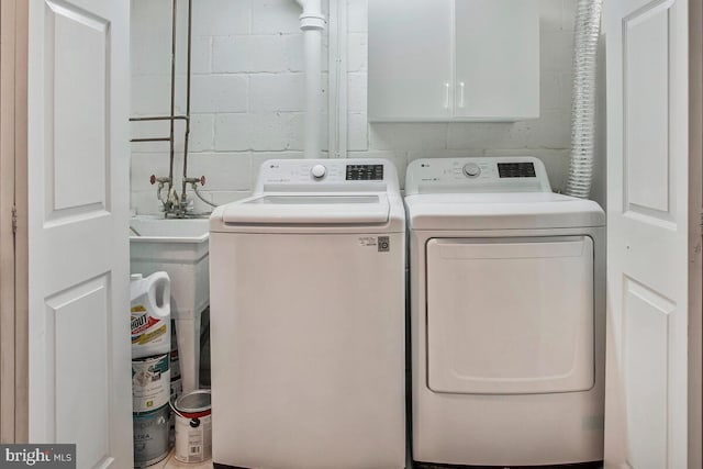 7215 Conley St, Baltimore, MD 21224 - laundry area with washer and clothes dryer, cabinet space, and concrete block wall