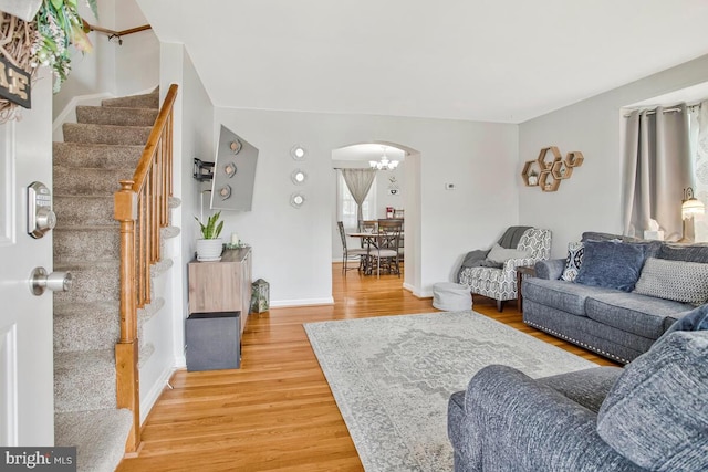 7215 Conley St, Baltimore, MD 21224 - living room featuring arched walkways, stairway, light wood finished floors, baseboards, and a chandelier