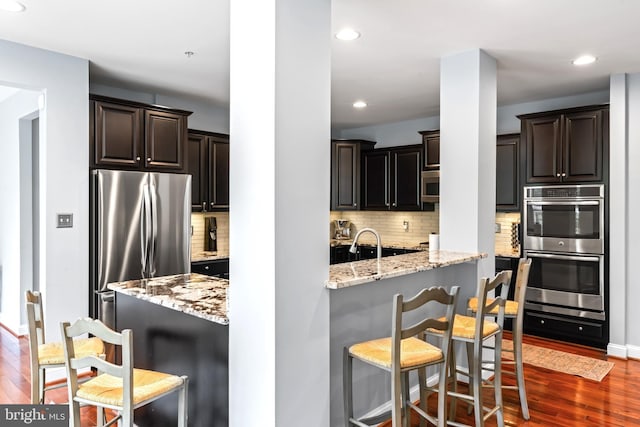 4300 Mountain Laurel Way, Brandywine, MD 20613 - kitchen featuring stainless steel appliances, dark wood finished floors, light stone counters, a breakfast bar area, and backsplash