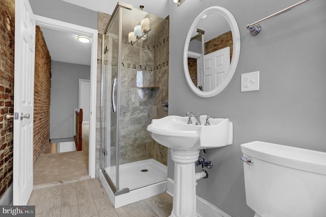 503 W 27th St, Baltimore, MD 21211 - bathroom with toilet, a stall shower, brick wall, wood finished floors, and baseboards