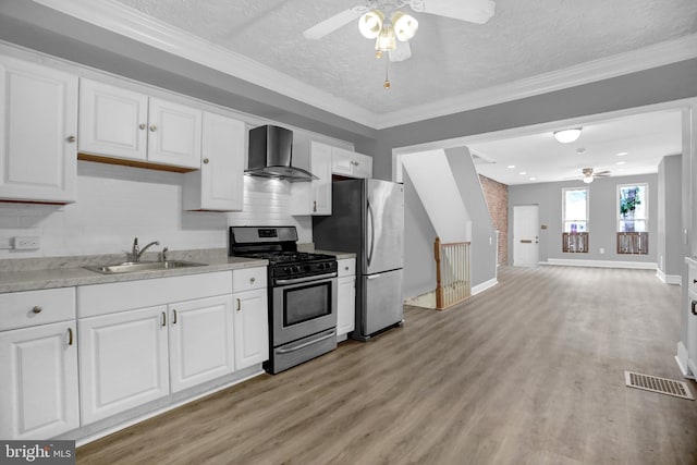 503 W 27th St, Baltimore, MD 21211 - kitchen featuring wall chimney exhaust hood, appliances with stainless steel finishes, a ceiling fan, a sink, and light wood-style floors