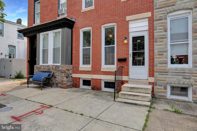 503 W 27th St, Baltimore, MD 21211 - view of exterior entry featuring stone siding, a patio area, and brick siding