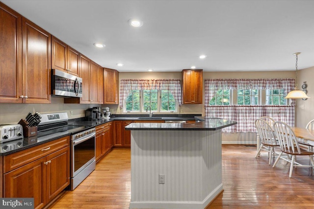 1381 Sunwood Ter, Annapolis, MD 21409 - kitchen featuring stainless steel appliances, a sink, light wood-style flooring, brown cabinetry, and a kitchen island
