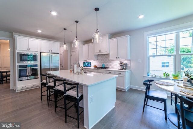 233 W Ponds Edge Dr, Media, PA 19063 - kitchen with built in appliances, dark wood-style flooring, decorative backsplash, light countertops, and a kitchen breakfast bar