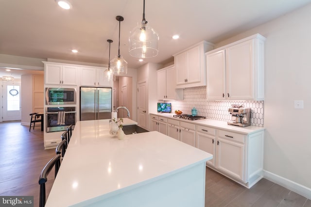 233 W Ponds Edge Dr, Media, PA 19063 - kitchen featuring built in appliances, tasteful backsplash, light wood finished floors, white cabinetry, and a kitchen island with sink