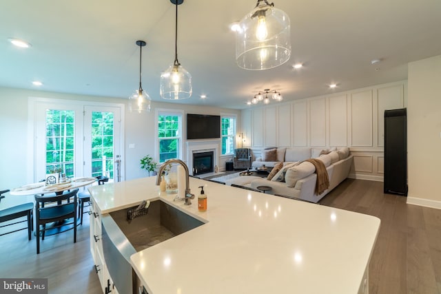233 W Ponds Edge Dr, Media, PA 19063 - kitchen featuring a sink, wood finished floors, light countertops, a glass covered fireplace, and a decorative wall