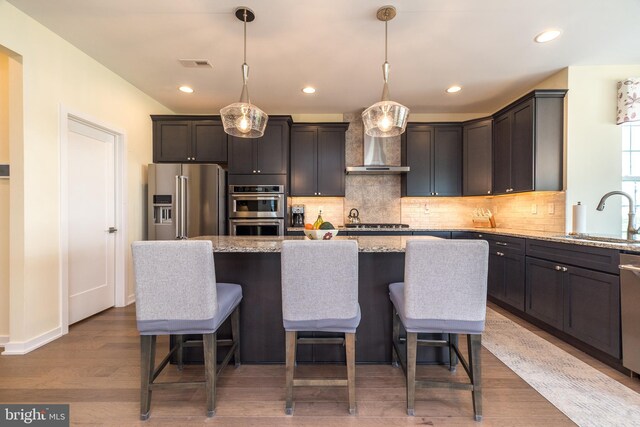 2038 Morgan Creek Dr, Quakertown, PA 18951 - kitchen featuring a sink, stainless steel appliances, wall chimney exhaust hood, light stone counters, and backsplash