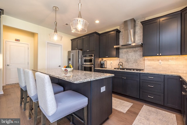 2038 Morgan Creek Dr, Quakertown, PA 18951 - kitchen with wall chimney range hood, stainless steel appliances, a kitchen island, light stone countertops, and wood finished floors