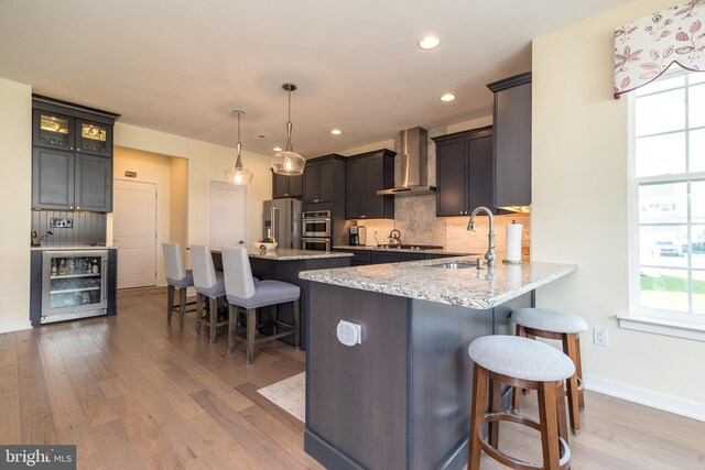 2038 Morgan Creek Dr, Quakertown, PA 18951 - kitchen featuring wall chimney range hood, beverage cooler, a sink, a kitchen bar, and wood finished floors