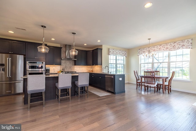 2038 Morgan Creek Dr, Quakertown, PA 18951 - kitchen with appliances with stainless steel finishes, wall chimney range hood, a chandelier, baseboards, and a breakfast bar area