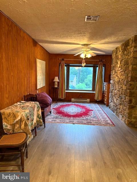 425 Beechcroft Rd, Winchester, VA 22601 - bedroom with a textured ceiling, wood-type flooring, wooden walls, an AC wall unit, and ceiling fan