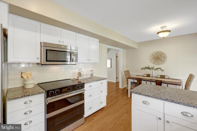 4212 Penner Ln, Fairfax, VA 22033 - kitchen with stainless steel microwave, double oven range, light wood-type flooring, tasteful backsplash, and white cabinets