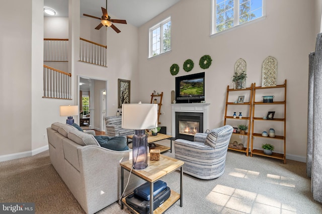 6000 Clairemont Dr, Owings, MD 20736 - living area with a high ceiling, carpet floors, a glass covered fireplace, ceiling fan, and baseboards