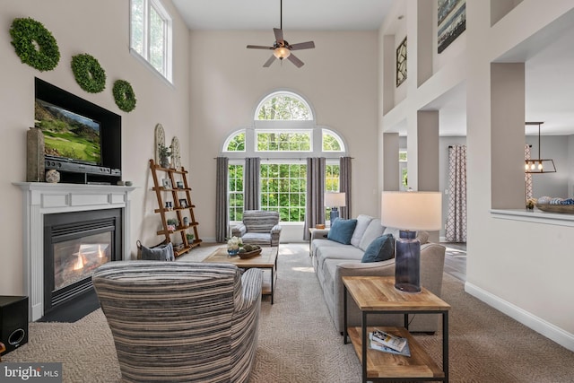 6000 Clairemont Dr, Owings, MD 20736 - carpeted living area featuring a towering ceiling, a glass covered fireplace, a ceiling fan, and baseboards