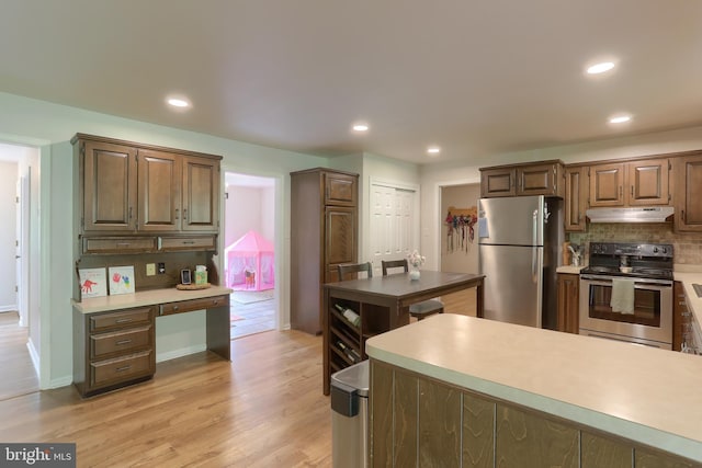 46 Gelsinger Rd, Reading, PA 19608 - kitchen featuring stainless steel appliances, under cabinet range hood, tasteful backsplash, light wood-type flooring, and light countertops