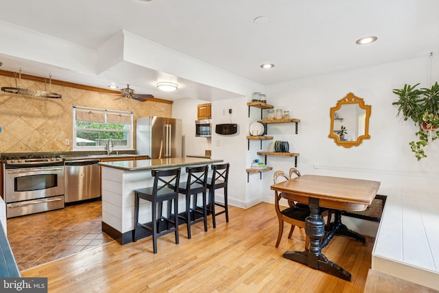 5721 Greenspring Ave, Baltimore, MD 21209 - kitchen featuring appliances with stainless steel finishes, a breakfast bar area, backsplash, light wood-style flooring, and recessed lighting