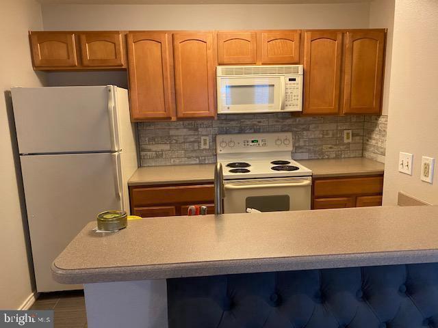 3916 Penderview Dr Unit 435, Fairfax, VA 22033 - kitchen with white appliances, light countertops, decorative backsplash, and brown cabinets