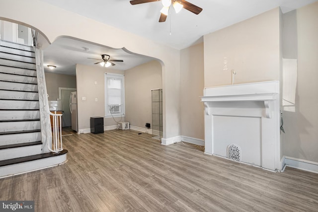 2729 W Seltzer St, Philadelphia, PA 19132 - unfurnished living room with arched walkways, a ceiling fan, stairs, and wood finished floors