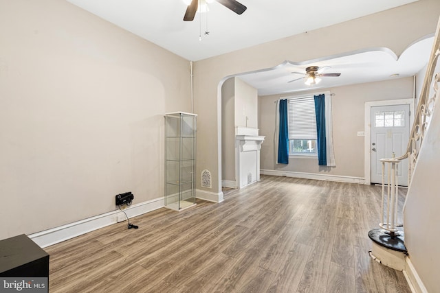 2729 W Seltzer St, Philadelphia, PA 19132 - unfurnished living room featuring ceiling fan, wood finished floors, arched walkways, baseboards, and stairway