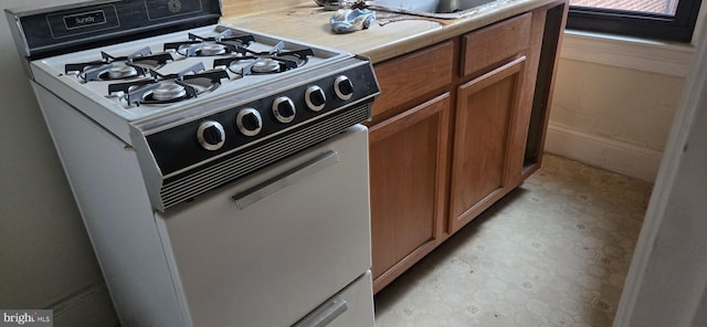 1101 L St NW Unit 406, Washington, DC 20005 - kitchen featuring white gas range, brown cabinets, and light countertops