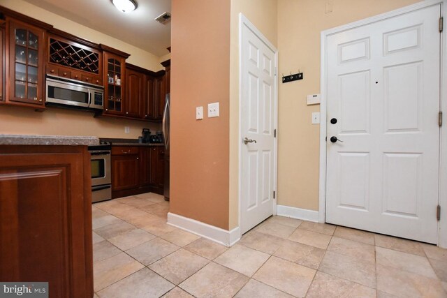 605 N Atlantic Ave Unit 204, Collingswood, NJ 08108 - kitchen featuring appliances with stainless steel finishes, glass insert cabinets, baseboards, and dark countertops