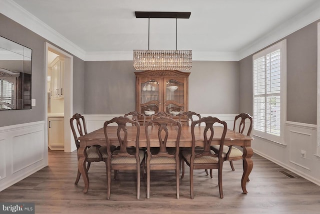 42863 Glyndebourne Ct, Broadlands, VA 20148 - dining room featuring a chandelier, a wainscoted wall, a decorative wall, wood finished floors, and crown molding