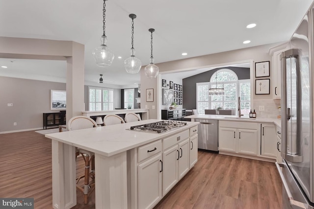 42863 Glyndebourne Ct, Broadlands, VA 20148 - kitchen with appliances with stainless steel finishes, a kitchen bar, a sink, light wood finished floors, and a center island