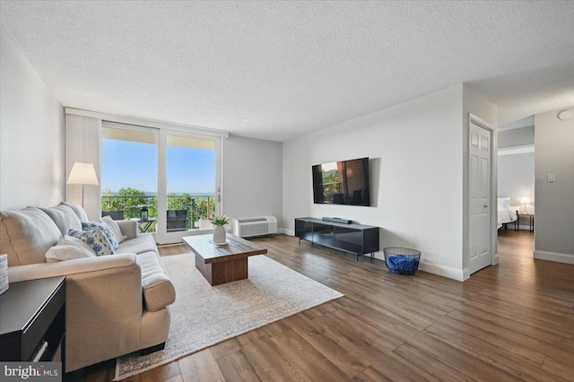 666 W Germantown Pike Unit 1706, Plymouth Meeting, PA 19462 - living room featuring a textured ceiling, wood finished floors, a wall mounted air conditioner, and baseboards