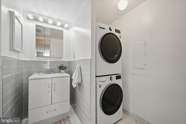 666 W Germantown Pike Unit 1706, Plymouth Meeting, PA 19462 - washroom featuring stacked washer and clothes dryer, electric panel, tile walls, and light marble finish floors