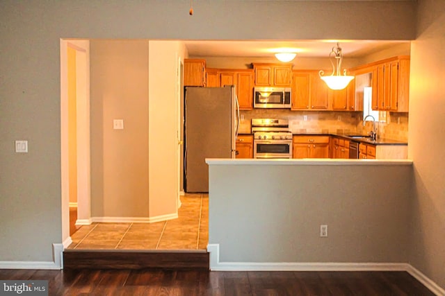 8 Spur Ridge Ct, Newark, DE 19702 - kitchen with stainless steel appliances, wood finished floors, backsplash, and a peninsula