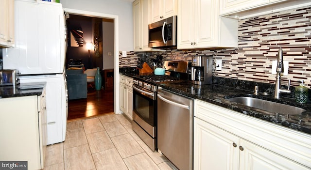 11839 Shire Ct Unit 31D, Reston, VA 20191 - kitchen with appliances with stainless steel finishes, a sink, stacked washer and clothes dryer, backsplash, and dark stone counters