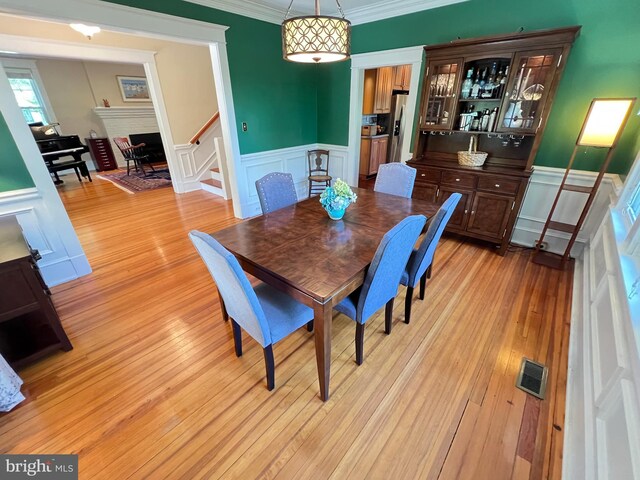 6206 Pinehurst Rd, Baltimore, MD 21212 - dining space featuring stairs, a decorative wall, ornamental molding, a wainscoted wall, and light wood-style floors