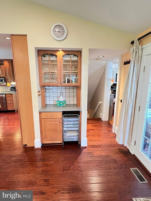 6206 Pinehurst Rd, Baltimore, MD 21212 - indoor dry bar with vaulted ceiling, dark wood-style floors, decorative backsplash, appliances with stainless steel finishes, and baseboards